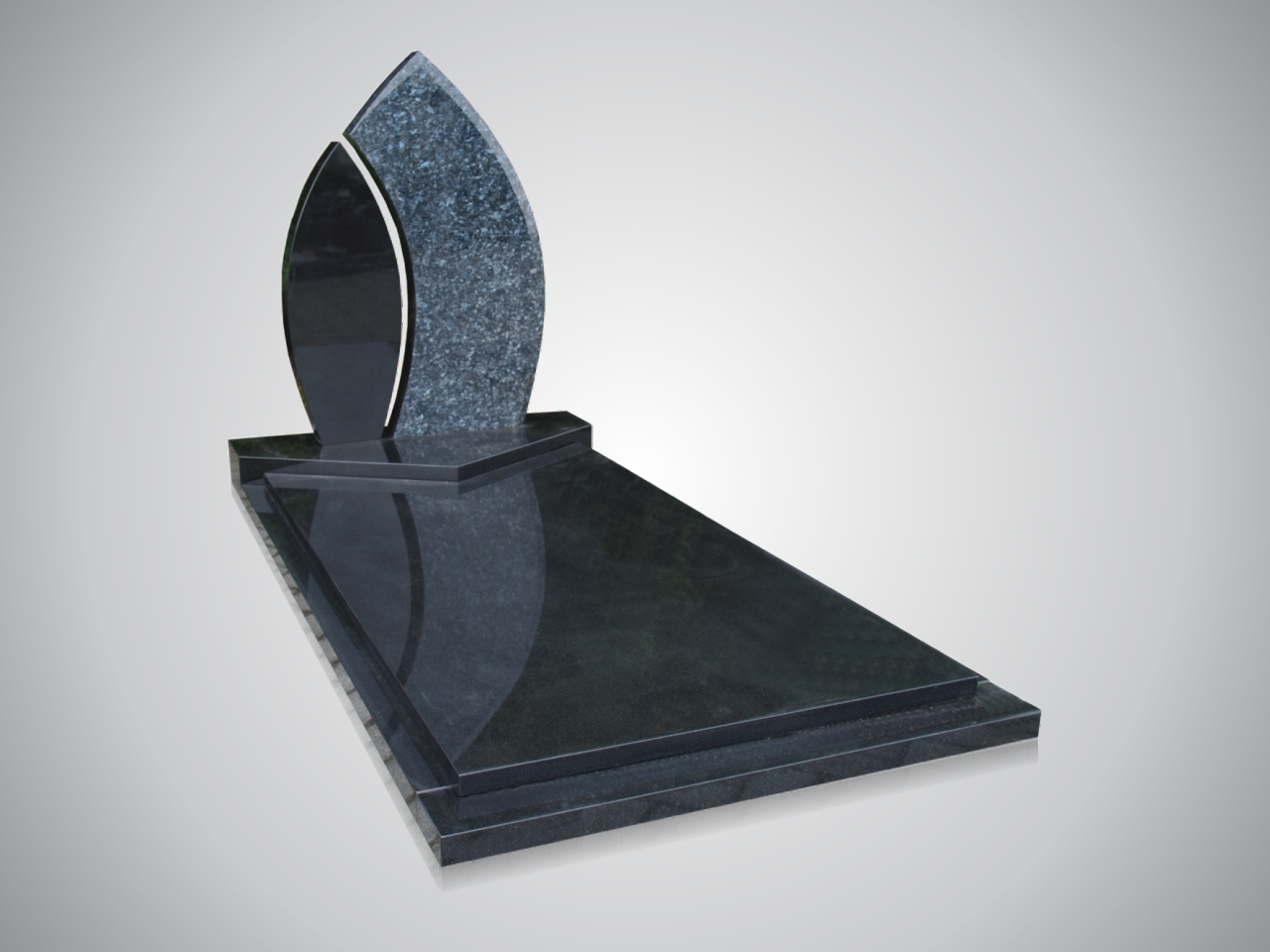 Modern familiegraf met vlamvormige grafsteen van zwart graniet, geplaatst op begraafplaats in Den Haag